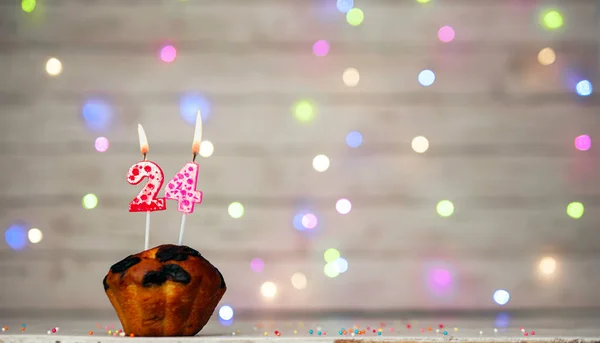 Happy birthday background with muffin and number of candles on light bulbs bokeh background. Greeting card happy birthday copy space with number 24