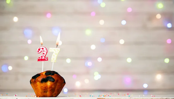 Happy birthday background with muffin and number of candles on light bulbs bokeh background. Greeting card happy birthday copy space with number 27