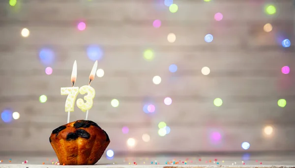 Happy birthday background with muffin and number of candles on light bulbs bokeh background. Greeting card happy birthday copy space with number 73