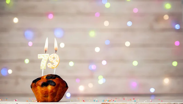 Happy birthday background with muffin and number of candles on light bulbs bokeh background. Greeting card happy birthday copy space with number 79