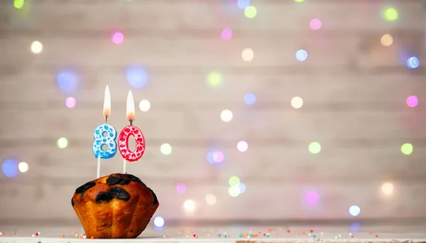 Happy birthday background with muffin and number of candles on light bulbs bokeh background. Greeting card happy birthday copy space with number 80