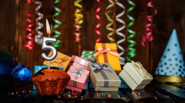 Birthday background with muffin and candles with number  5. Beautiful anniversary background with cake copy space with burning candles. Gift boxes with decorations.
