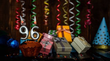 Birthday background with muffin and candles with number  96. Beautiful anniversary background with cake copy space with burning candles. Gift boxes with decorations.