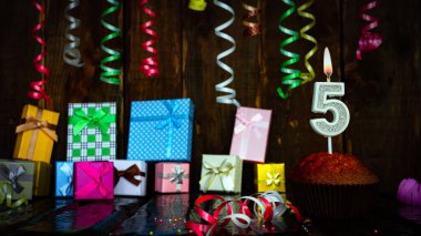 Party birthday background with number  5. Beautiful background anniversary copy space with burning candles. Gift boxes with decorations.