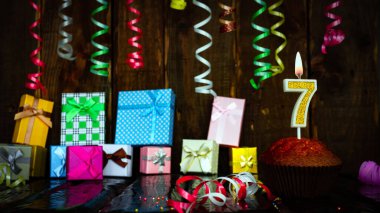 Party birthday background with number 7. Beautiful background anniversary copy space with burning candles. Gift boxes with decorations.