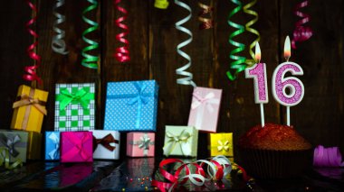 Party birthday background with number  16. Beautiful background anniversary copy space with burning candles. Gift boxes with decorations.