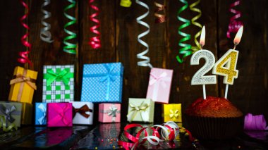 Party birthday background with number  24. Beautiful background anniversary copy space with burning candles. Gift boxes with decorations.