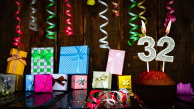 Party birthday background with number  32. Beautiful background anniversary copy space with burning candles. Gift boxes with decorations.
