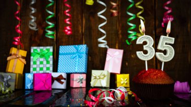 Party birthday background with number  35. Beautiful background anniversary copy space with burning candles. Gift boxes with decorations.