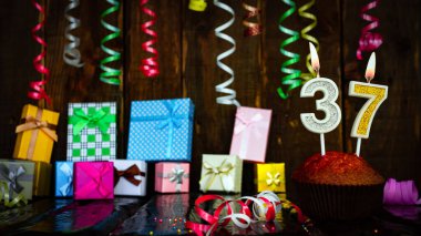 Party birthday background with number  37. Beautiful background anniversary copy space with burning candles. Gift boxes with decorations.