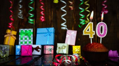 Party birthday background with number  40. Beautiful background anniversary copy space with burning candles. Gift boxes with decorations.