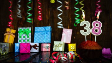 Party birthday background with number  38. Beautiful background anniversary copy space with burning candles. Gift boxes with decorations.