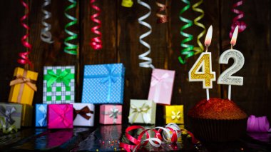 Party birthday background with number  42. Beautiful background anniversary copy space with burning candles. Gift boxes with decorations.