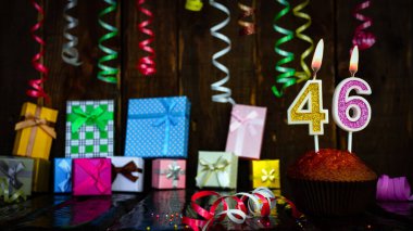 Party birthday background with number  46. Beautiful background anniversary copy space with burning candles. Gift boxes with decorations.