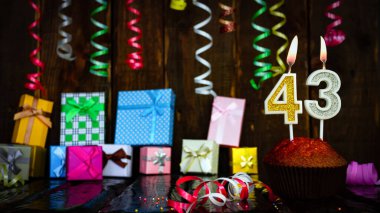 Party birthday background with number  43. Beautiful background anniversary copy space with burning candles. Gift boxes with decorations.