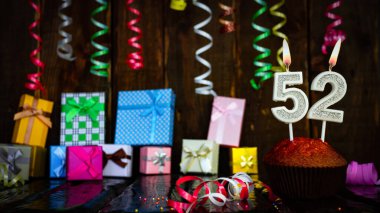 Party birthday background with number  52. Beautiful background anniversary copy space with burning candles. Gift boxes with decorations.