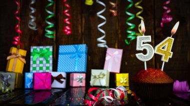 Party birthday background with number 54 . Beautiful background anniversary copy space with burning candles. Gift boxes with decorations.