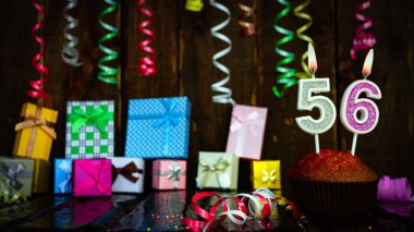Party birthday background with number  56. Beautiful background anniversary copy space with burning candles. Gift boxes with decorations.