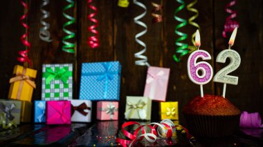 Party birthday background with number  62. Beautiful background anniversary copy space with burning candles. Gift boxes with decorations.