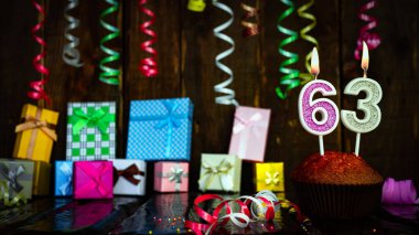 Party birthday background with number  63. Beautiful background anniversary copy space with burning candles. Gift boxes with decorations.