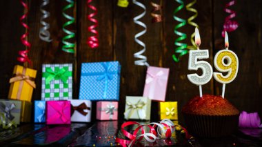 Party birthday background with number  59. Beautiful background anniversary copy space with burning candles. Gift boxes with decorations.