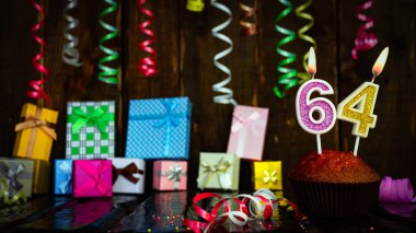 Party birthday background with number  64. Beautiful background anniversary copy space with burning candles. Gift boxes with decorations.
