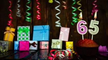 Party birthday background with number  65. Beautiful background anniversary copy space with burning candles. Gift boxes with decorations.