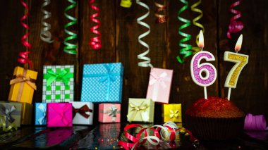 Party birthday background with number 67. Beautiful background anniversary copy space with burning candles. Gift boxes with decorations.