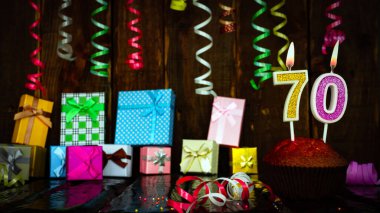 Party birthday background with number  70. Beautiful background anniversary copy space with burning candles. Gift boxes with decorations.