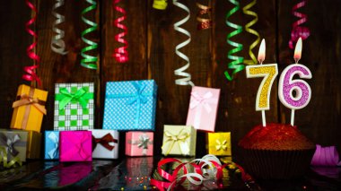 Party birthday background with number  76. Beautiful background anniversary copy space with burning candles. Gift boxes with decorations.