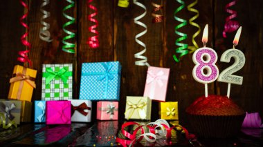 Party birthday background with number  82. Beautiful background anniversary copy space with burning candles. Gift boxes with decorations.