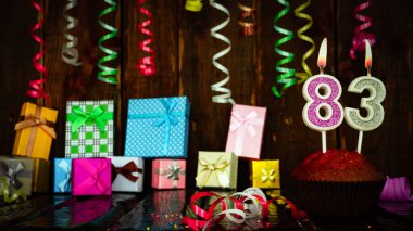 Party birthday background with number  83. Beautiful background anniversary copy space with burning candles. Gift boxes with decorations.