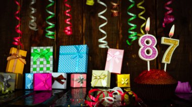 Party birthday background with number  87. Beautiful background anniversary copy space with burning candles. Gift boxes with decorations.
