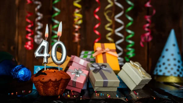Birthday background with muffin and candles with number  40. Beautiful anniversary background with cake copy space with burning candles. Gift boxes with decorations.