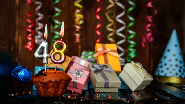 Birthday background with muffin and candles with number  48. Beautiful anniversary background with cake copy space with burning candles. Gift boxes with decorations.