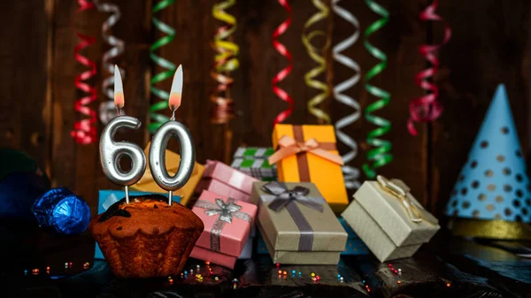 Birthday background with muffin and candles with number  60. Beautiful anniversary background with cake copy space with burning candles. Gift boxes with decorations.