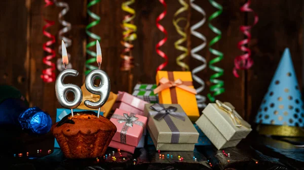 Birthday background with muffin and candles with number  69. Beautiful anniversary background with cake copy space with burning candles. Gift boxes with decorations.