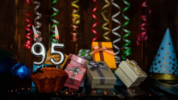 Birthday background with muffin and candles with number  95. Beautiful anniversary background with cake copy space with burning candles. Gift boxes with decorations.
