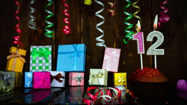 Party birthday background with number 12. Beautiful background anniversary copy space with burning candles. Gift boxes with decorations.