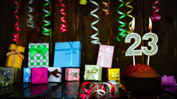 Party birthday background with number  23. Beautiful background anniversary copy space with burning candles. Gift boxes with decorations.