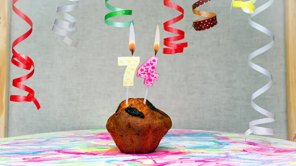 Happy birthday background with muffin with beautiful decorations with number candles  74. Colorful festive card happy birthday with a number. Anniversary copy space