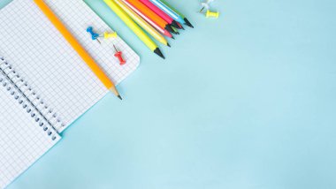 Üst görünüm Notepad ile boş bir sayfa ve yazıtlar için kafesin içinde bir sayfa. Ahşap bir masanın üzerinde renkli kalemlerle yazılmış bir yazı için boş. Kırtasiye Arkaplanı Mavi arkaplan üzerine yazmak için boş bir planlayıcı.