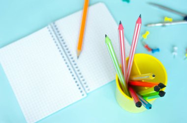 Üst görünüm Notepad turkuazının siyah tuşlu bir kalemle boş bir sayfası var. Ahşap bir masanın üzerinde renkli kalemlerle yazılmış bir yazı için boş. Kırtasiye Arkaplanı Mavi arkaplan üzerine yazmak için boş bir planlayıcı