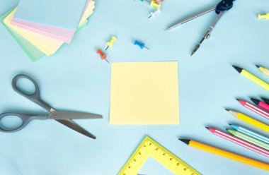 Üzerinde yazıtlar için sayfa olan boş bir sayfası olan üst görünüm not defteri sarı karesi. Ahşap bir masanın üzerinde renkli kalemlerle yazılmış bir yazı için boş. Kırtasiye Arkaplanı Mavi arkaplan üzerine yazmak için boş bir planlayıcı.
