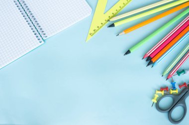 Üzerinde siyah tuşlu kalem olan bir kafesin içinde boş bir sayfa olan üst görünüm not defteri. Ahşap bir masanın üzerinde renkli kalemlerle yazılmış bir yazı için boş. Kırtasiye Arkaplanı Kol düğmeleri ve makas ile yazmak için boş.