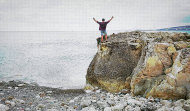 Happy man on top of a mountain with his hands up in the background of the sea. Dreamy man on the mountain. The man looks at the sea.