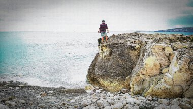 Illustration Happy man on top of a mountain against the backdrop of the sea. Dreamy man on the mountain. The man looks at the sea.