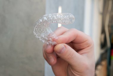 The model is a plastic plate for teeth bruxism, a cap for straightening teeth or an aligner. The concept of healthy teeth in men