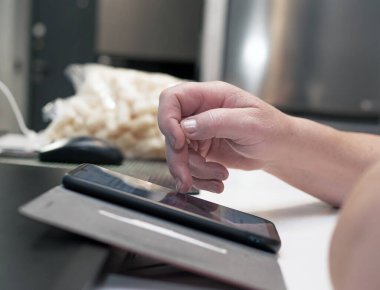 The hands of an elderly woman swipe a touchscreen smartphone.