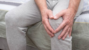 Knee pain in an elderly man. An old man holding his hand clutching his knee. Problems or injury with a patella calyx. Massage your foot.